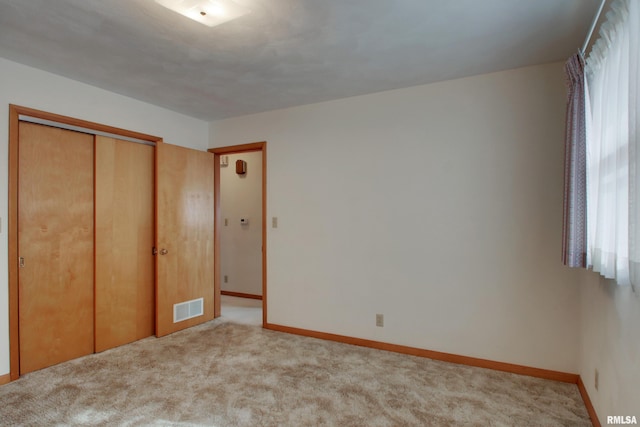 unfurnished bedroom with light colored carpet and a closet