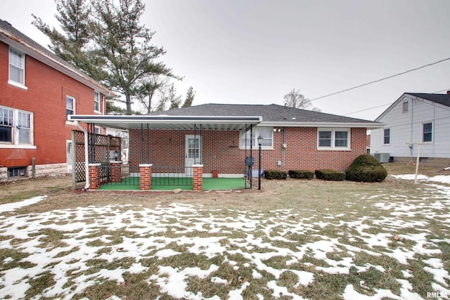 snow covered house featuring a porch and central AC