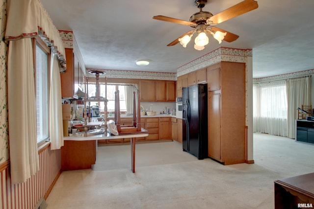 kitchen featuring light colored carpet, a wealth of natural light, and black fridge