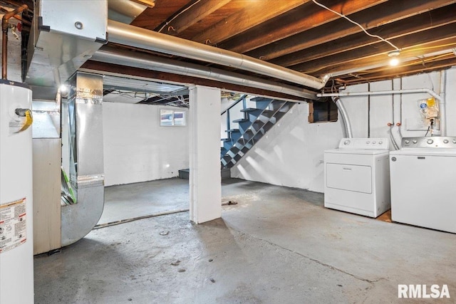 basement featuring water heater, heating unit, and washer and dryer