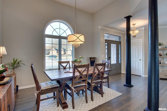 dining room with dark wood-type flooring, ornamental molding, ornate columns, and a chandelier