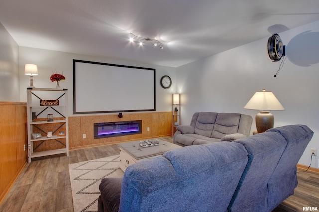 cinema room with wood-type flooring, track lighting, and wooden walls