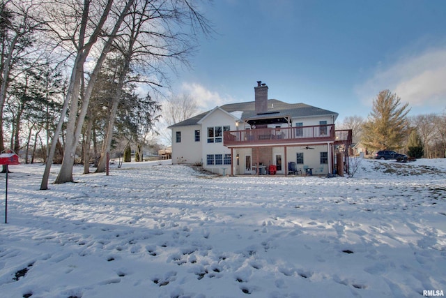 snow covered back of property featuring a wooden deck