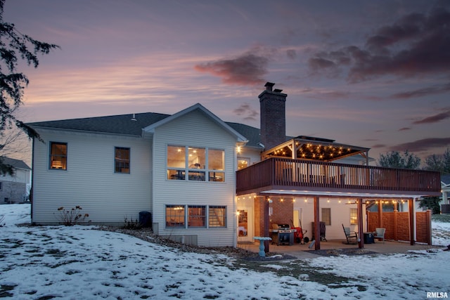 snow covered rear of property featuring a deck