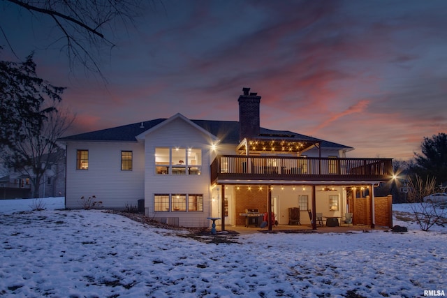 snow covered back of property with a wooden deck