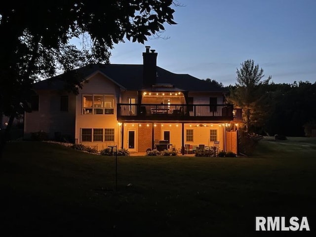 back house at dusk with a wooden deck and a yard