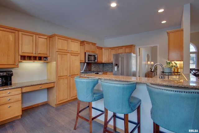 kitchen featuring light stone countertops, appliances with stainless steel finishes, dark hardwood / wood-style flooring, and built in desk