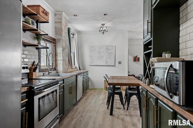 kitchen featuring crown molding, appliances with stainless steel finishes, sink, a textured ceiling, and light hardwood / wood-style floors