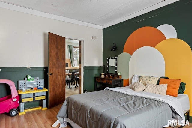 bedroom with light hardwood / wood-style flooring, a textured ceiling, and crown molding