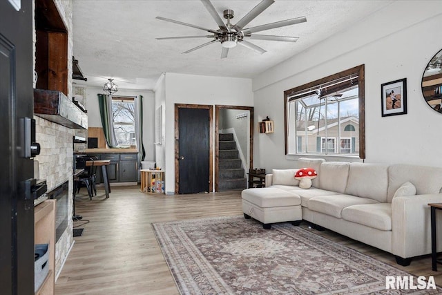 living room featuring ceiling fan, light hardwood / wood-style floors, and a textured ceiling