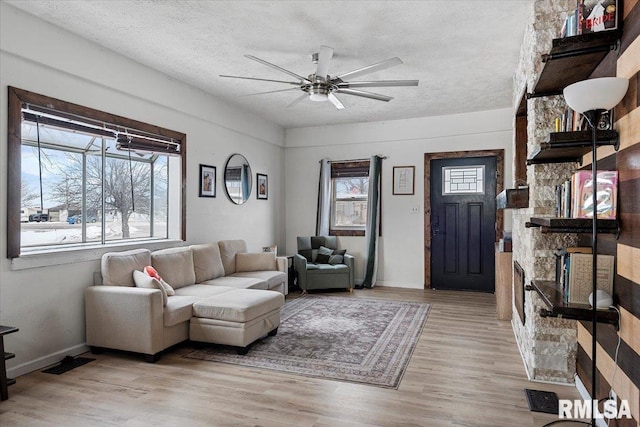 living room with light hardwood / wood-style floors, a textured ceiling, and ceiling fan