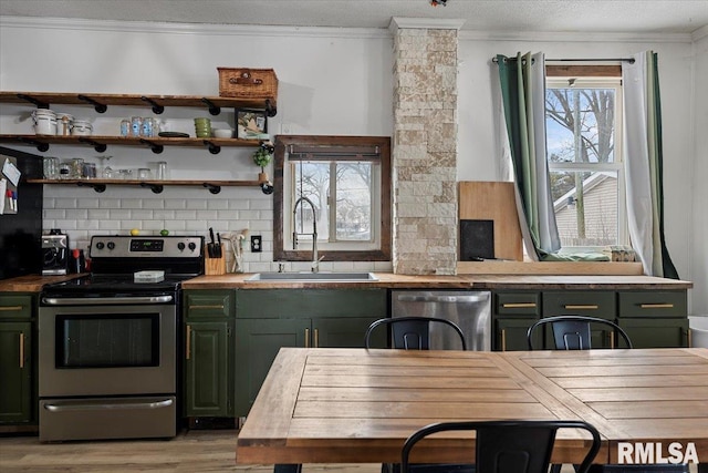 kitchen with appliances with stainless steel finishes, sink, backsplash, ornamental molding, and green cabinetry