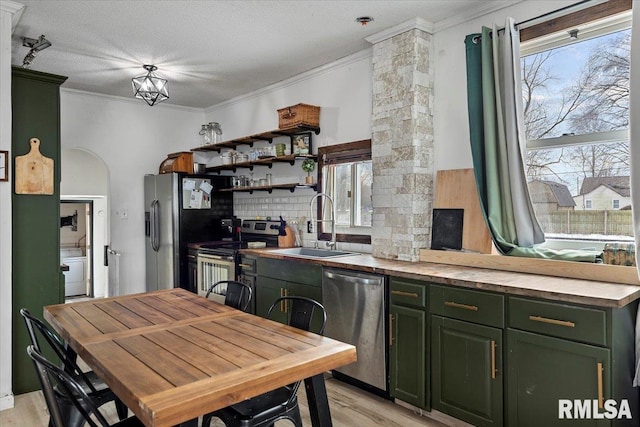 kitchen featuring a wealth of natural light, appliances with stainless steel finishes, green cabinetry, sink, and light hardwood / wood-style flooring