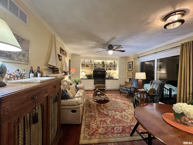 living room featuring ceiling fan, dark wood-type flooring, built in features, and ornamental molding