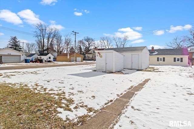 yard layered in snow featuring a garage and a shed