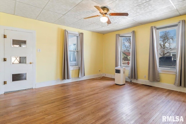 empty room with ceiling fan, a paneled ceiling, and hardwood / wood-style floors