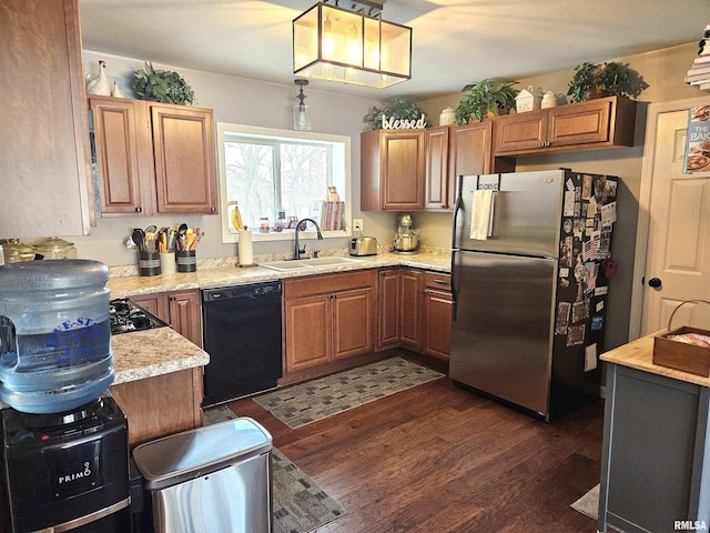 kitchen with decorative light fixtures, sink, light stone counters, black appliances, and dark wood-type flooring