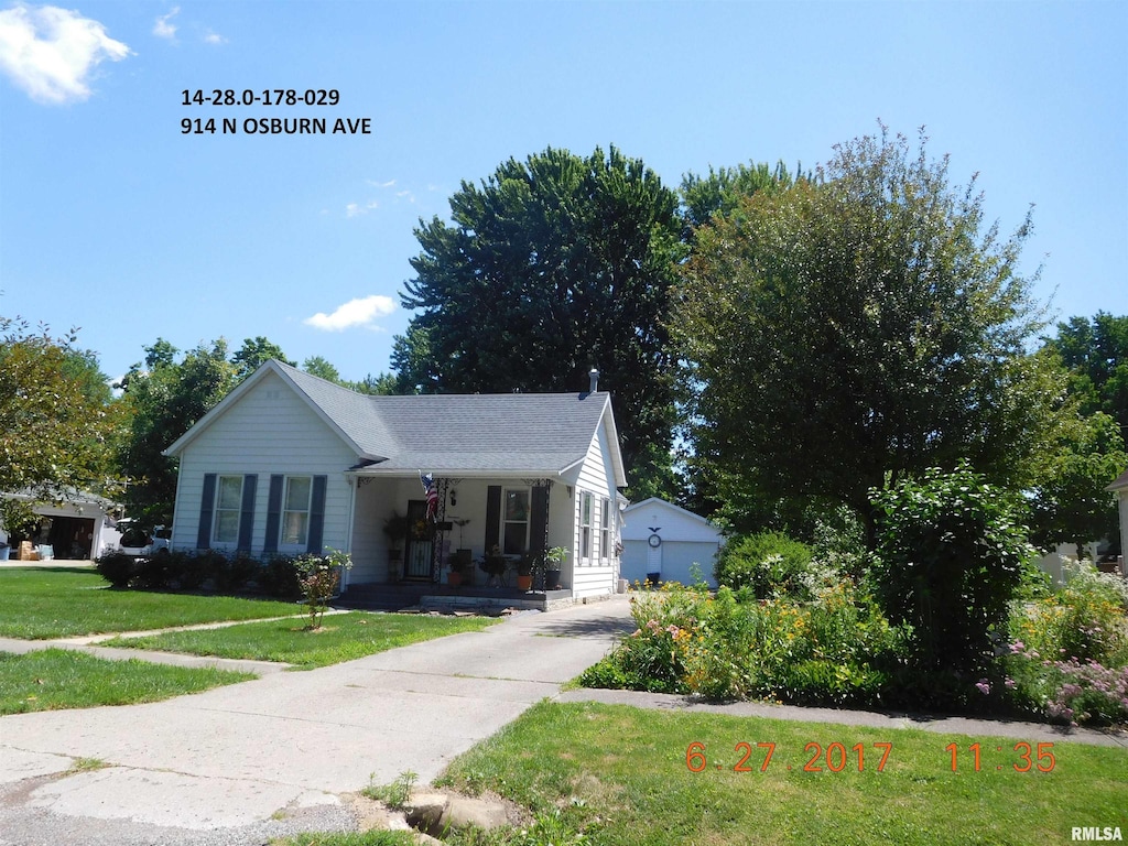 view of front facade featuring an outbuilding, a garage, a front lawn, and a porch