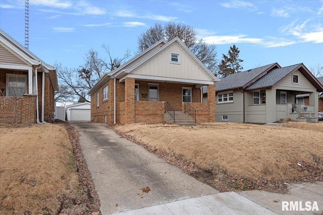 bungalow with a garage, a porch, and an outbuilding