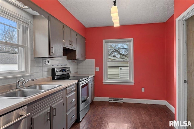 kitchen with sink, dark wood-type flooring, appliances with stainless steel finishes, hanging light fixtures, and plenty of natural light