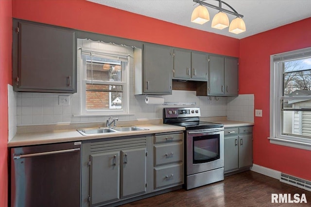 kitchen featuring dark wood-type flooring, sink, decorative light fixtures, gray cabinets, and stainless steel appliances