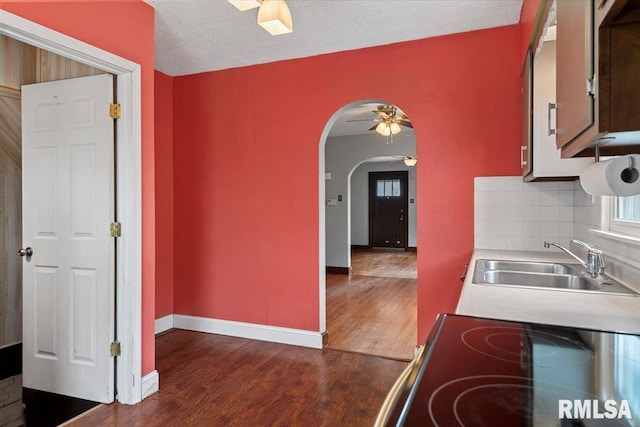 kitchen with sink, dark wood-type flooring, backsplash, and ceiling fan