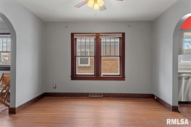 empty room with ceiling fan, plenty of natural light, and light wood-type flooring