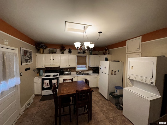 kitchen with range with gas stovetop, white fridge, a notable chandelier, stacked washing maching and dryer, and white cabinets