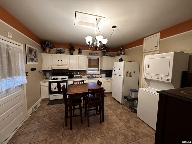 kitchen with stacked washer and clothes dryer, white cabinetry, hanging light fixtures, a notable chandelier, and white appliances