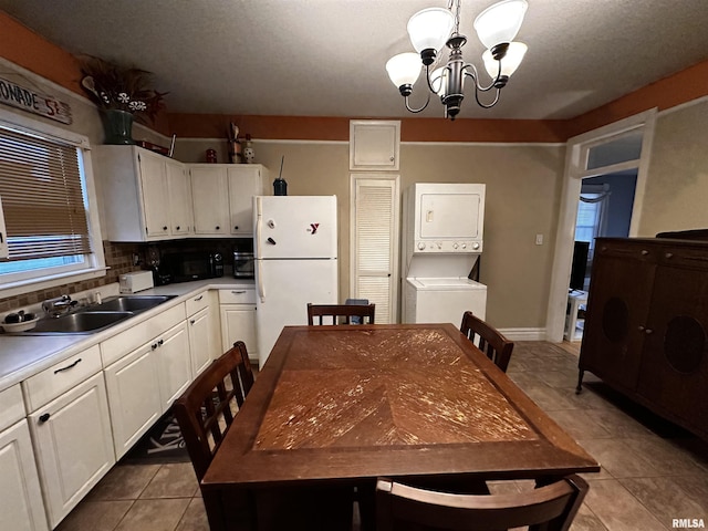 kitchen with stacked washer and dryer, sink, white cabinetry, hanging light fixtures, and white refrigerator