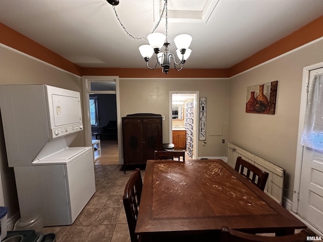 dining area with an inviting chandelier, tile patterned floors, and stacked washer / dryer