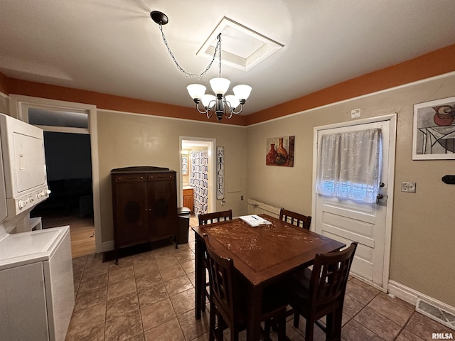 dining area with stacked washer / dryer and a notable chandelier