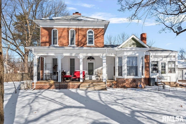 snow covered back of property with covered porch