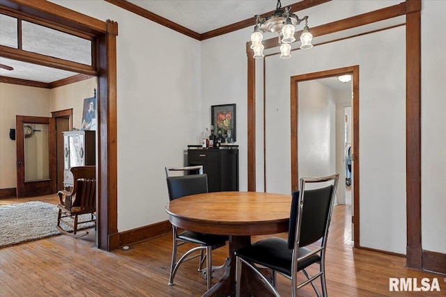 dining room with crown molding, hardwood / wood-style floors, and a chandelier