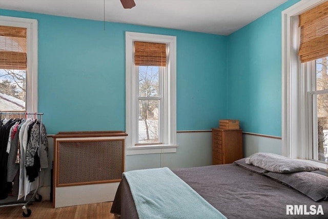 bedroom with multiple windows, hardwood / wood-style floors, and ceiling fan