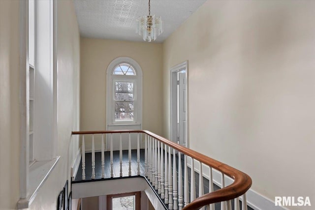 stairs featuring an inviting chandelier and a textured ceiling