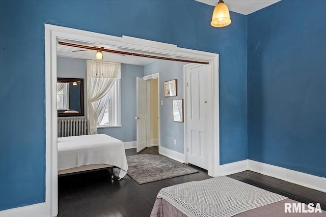 bedroom with dark hardwood / wood-style floors and radiator