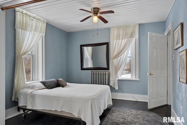 bedroom with dark hardwood / wood-style flooring, radiator heating unit, and ceiling fan