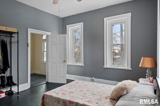 bedroom with dark wood-type flooring, ceiling fan, a closet, and multiple windows