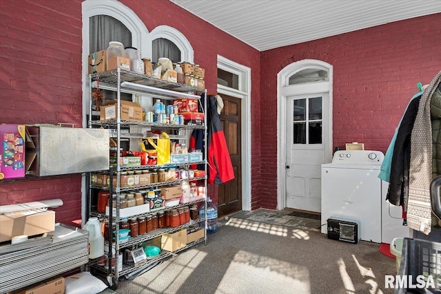 interior space featuring carpet floors, washing machine and clothes dryer, and brick wall