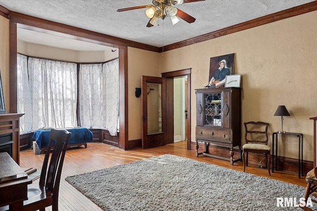 bedroom with crown molding, ceiling fan, hardwood / wood-style floors, and a textured ceiling