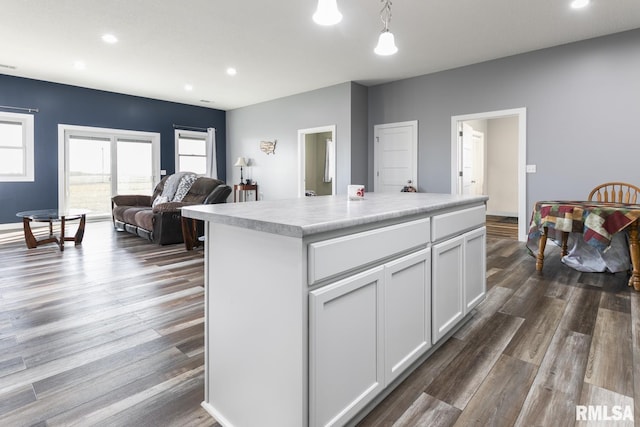 kitchen featuring white cabinetry, a center island, pendant lighting, and dark hardwood / wood-style flooring