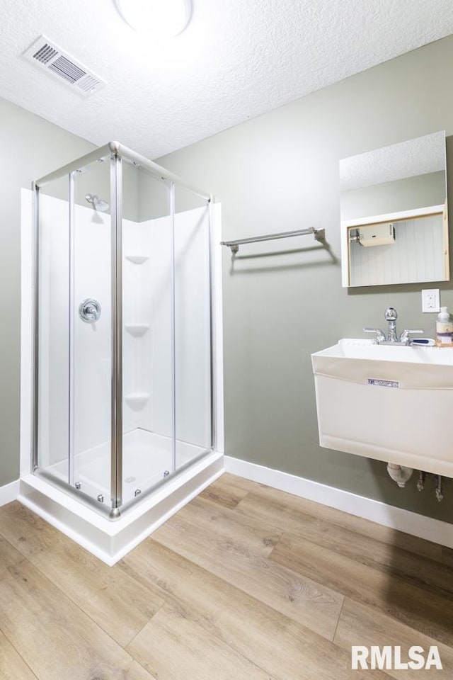 bathroom featuring hardwood / wood-style floors, sink, a textured ceiling, and walk in shower