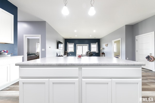 kitchen with light hardwood / wood-style flooring, a kitchen island, hanging light fixtures, and white cabinets