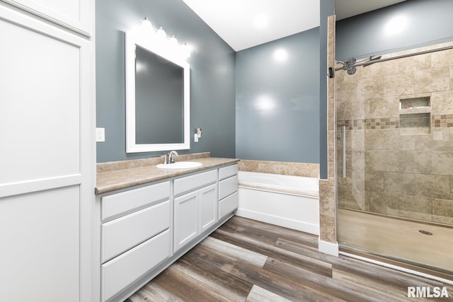 bathroom featuring hardwood / wood-style flooring, plus walk in shower, and vanity