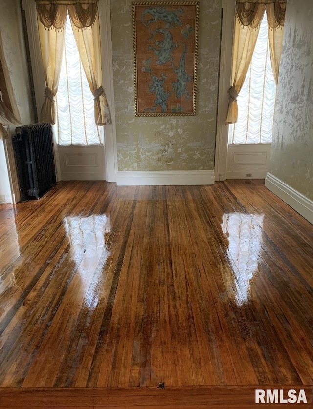 empty room with wood-type flooring, radiator, and a wealth of natural light