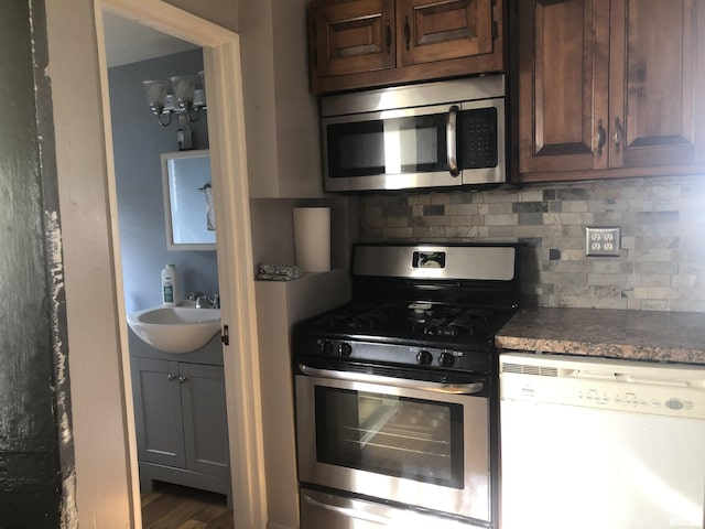 kitchen featuring sink, backsplash, dark brown cabinets, and appliances with stainless steel finishes