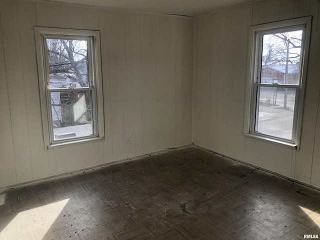 spare room featuring dark parquet flooring and a healthy amount of sunlight