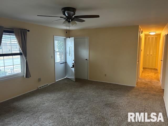 empty room featuring carpet, a healthy amount of sunlight, and ceiling fan