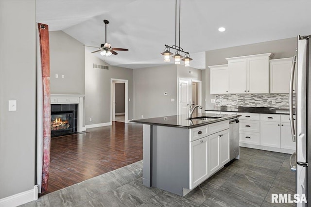 kitchen featuring sink, vaulted ceiling, an island with sink, stainless steel appliances, and white cabinets